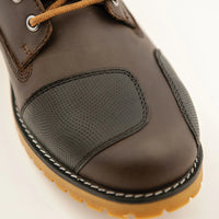 Brown leather shoe closeup of a toe shifter pad with a yellow sole on a light background