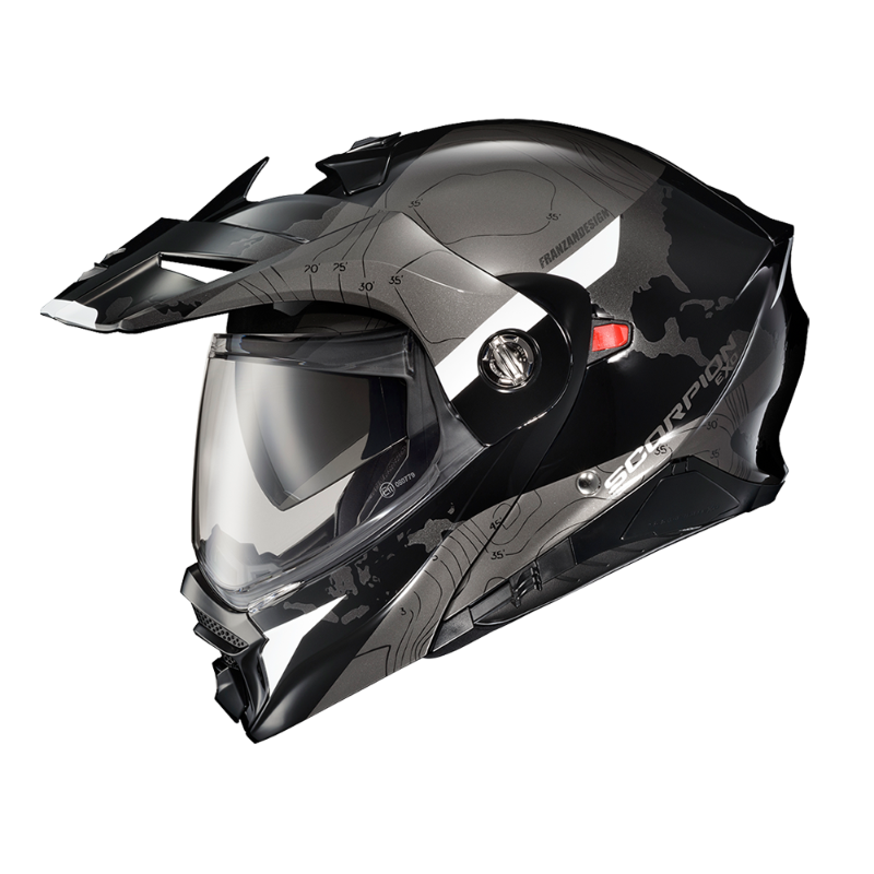 Scorpion EXO-AT960 Topographic Modular Adventure Motorcycle Helmet in Black/White. This dual-sport helmet features a rugged matte black finish with grey topographic map graphics and white accent panels. It includes an aerodynamic adventure peak visor, clear EverClear® face shield, integrated drop-down sun visor, and a modular flip-up chin bar for versatility. Designed for both on-road touring and off-road adventure riding, the EXO-AT960 combines aggressive styling with advanced ventilation, premium comfort,