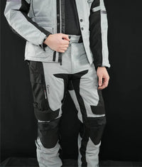 Man wearing Gryphon Men’s Pacific Coast grey and black adventure motorcycle pants with reinforced knees and matching jacket, front view.