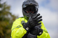 Person wearing a bright yellow jacket, and Gryphon Amazon black waterproof motorcycle gloves, and a helmet outdoors.