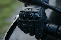 Black motorcycle glove on a handlebar with a blurred background