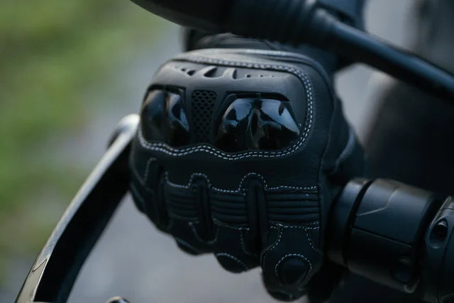 Black motorcycle glove on a handlebar with a blurred background