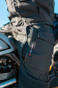 Close-up of Gryphon Women’s Pacific Coast 2 black motorcycle pants showing the zippered Air Flow System thigh vent and adjustable knee strap.