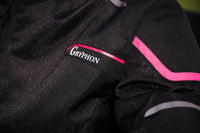 Close-up of the Gryphon Women’s AQUA AIR mesh motorcycle jacket in black, highlighting the breathable high-flow mesh fabric, Gryphon chest logo, reinforced shoulder panel and bright pink and reflective silver accents.