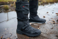 Joe Rocket Ballistic Men's Adventure Motorcycle Boots worn outdoors in wet, muddy conditions, showcasing the waterproof tall ADV boot design, adjustable quick-release buckles, reinforced shin and ankle protection, and rugged high-traction outsole built for adventure touring, dual-sport, and off-road motorcycle riding.