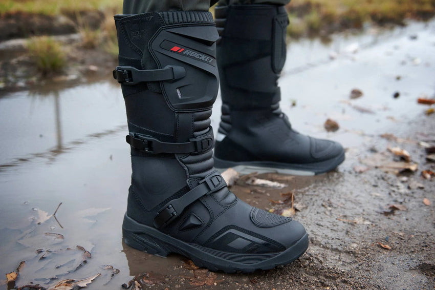 Joe Rocket Ballistic Men's Adventure Motorcycle Boots worn outdoors in wet, muddy conditions, showcasing the waterproof tall ADV boot design, adjustable quick-release buckles, reinforced shin and ankle protection, and rugged high-traction outsole built for adventure touring, dual-sport, and off-road motorcycle riding.