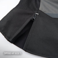 Close-up of a black zippered hip gusset on a sports training top, showing the black mesh fabric and a black zipper pull, with a text overlay reading 'ZIPPERED HIP GUSSETS'.