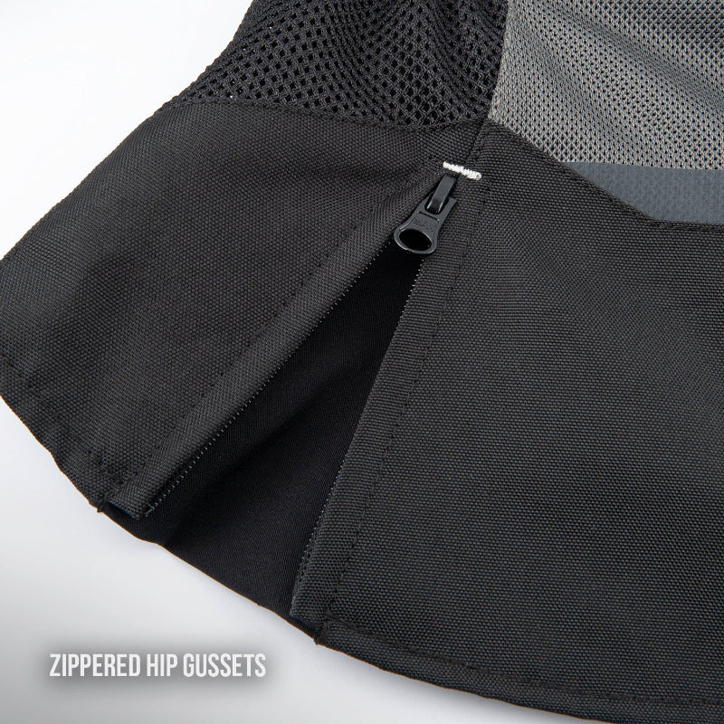 Close-up of a black zippered hip gusset on a sports training top, showing the black mesh fabric and a black zipper pull, with a text overlay reading 'ZIPPERED HIP GUSSETS'.