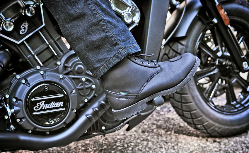 Lifestyle photo of the Joe Rocket Iron Age Waterproof Motorcycle Cruiser Boot in black being worn on an Indian motorcycle. The waterproof leather boot features a classic lace-up design, reinforced shift pad, and rugged lug sole, providing all-day comfort, protection, and traction for cruiser, touring, and everyday motorcycle riding.