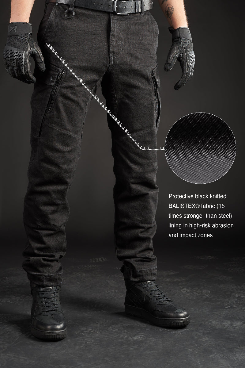 Person wearing black motorcycle cargo pants with text detailing material and features on a dark background