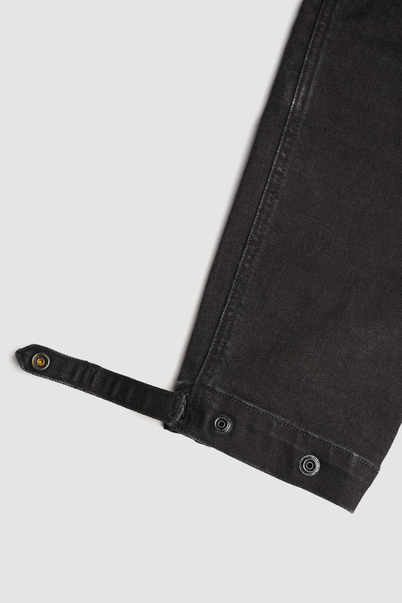 Close-up of black cargo motorcycle pantst with strap on a light gray background