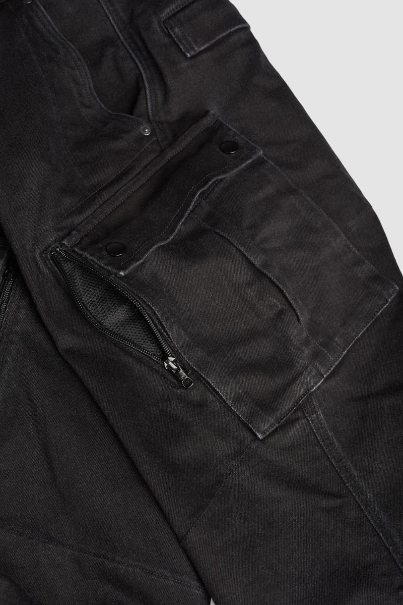 Close-up of black cargo motorcycle pants pocket with zippers and buttons on a light gray background