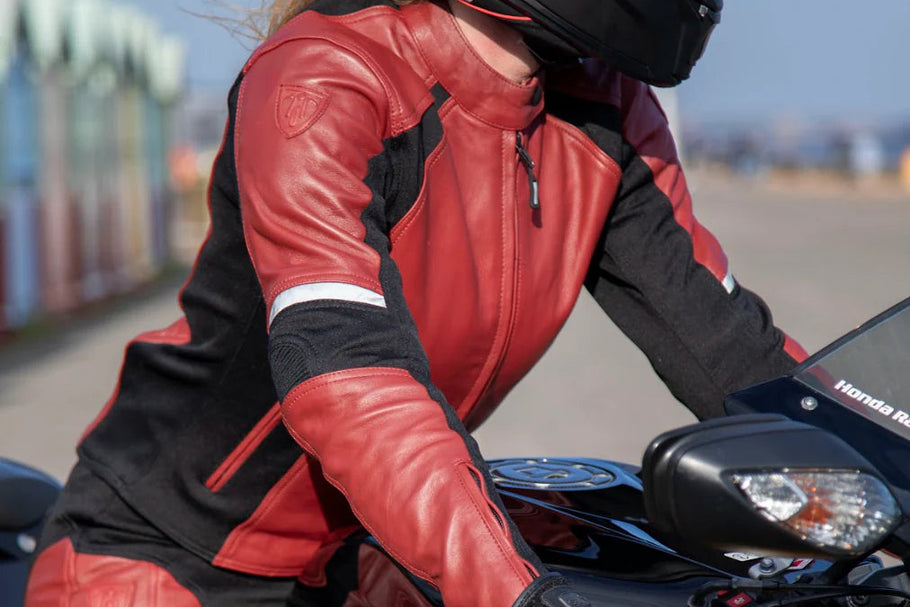 Person wearing a red and black motorcycle jacket on a motorcycle.