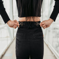 Rear close-up of MotoGirl ISLA black women's motorcycle jeans showing adjustable waist straps with metal buckles, belt loops and back pockets for a customizable fit.