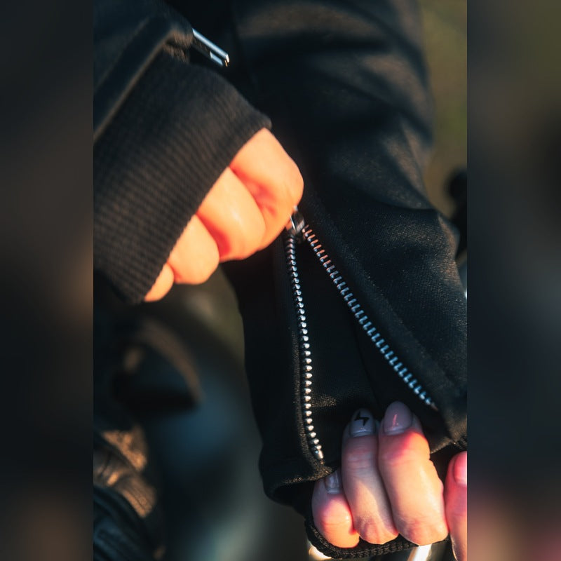 Close-up of the MotoGirl Sherrie black women's motorcycle jacket showing the open silver cuff zipper and ribbed inner cuff.