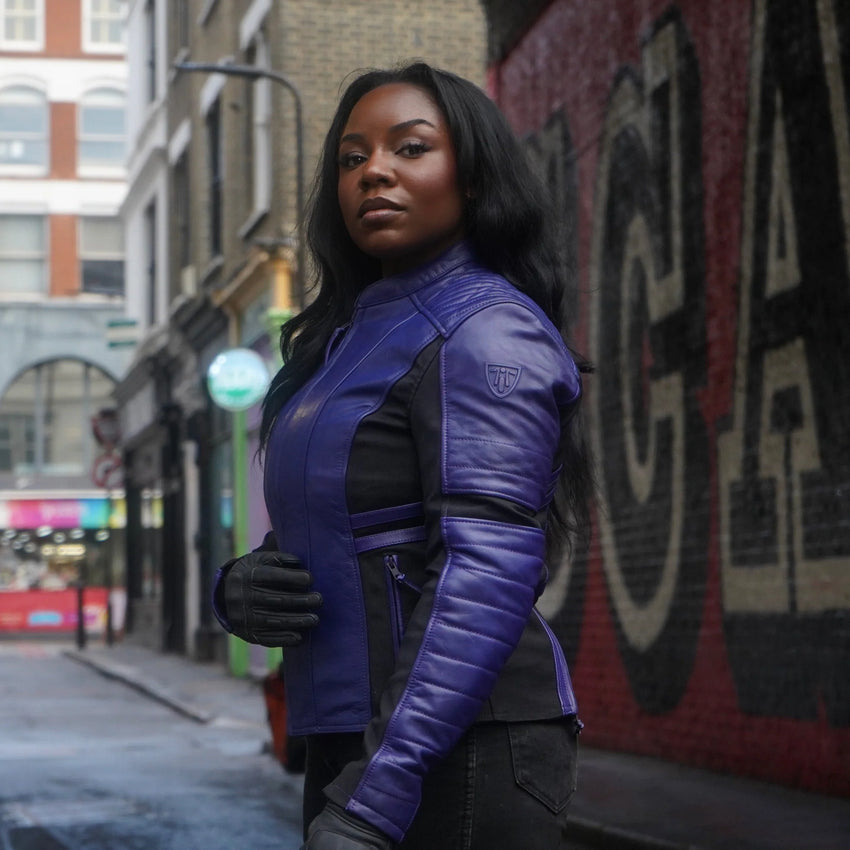 Woman wearing a branded Motogirl Amelia Leather jacket in purple on a city street with graffiti in the background