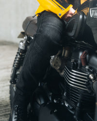 A Girl sitting on a motorcycle wearing a yellow leather Motorcycle jacket and black Ellie Jeans with a black lace up boot
