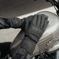 A person wearing black MotoGirl NANDI Winter Gloves on a motorcycle, showcasing the gloves' design and fit.
