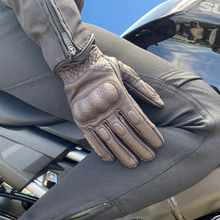 Motogirl branded Yoko brown motorcycle  gloves worn by a person sitting on a motorcycle with a blue sky in background