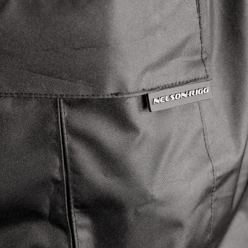 Close-up detail of the Nelson-Rigg SSJ SOLO STORM Motorcycle Rain Jacket showing the durable cargo pocket with flap closure and Nelson-Rigg logo tab. Constructed from waterproof polyester Oxford fabric with reinforced stitching, the pocket provides secure, weather-resistant storage for essential riding items.