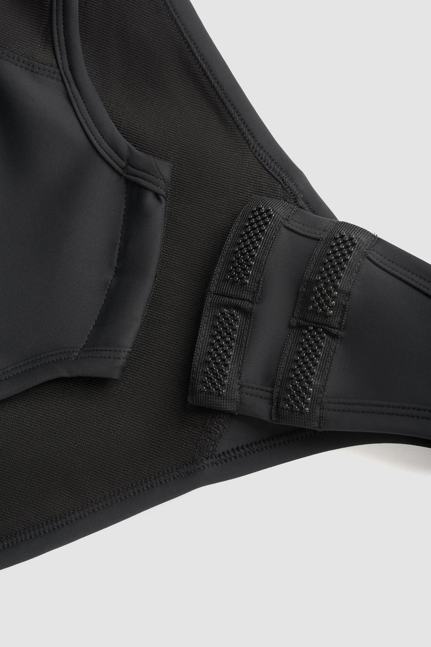 The closeup of the crotch closure system for the pando Moto Shell ww on a grey background