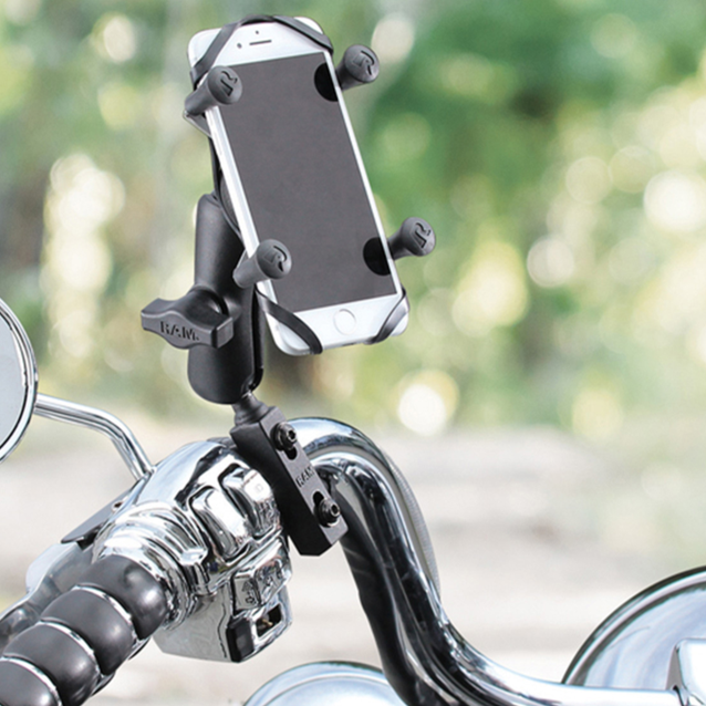 Phone holder on a motorcycle handlebar with a blurred natural background