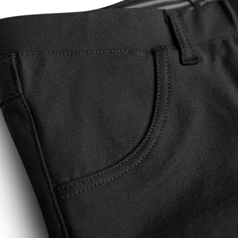 Close-up of black pants with a pocket detail on a light gray background