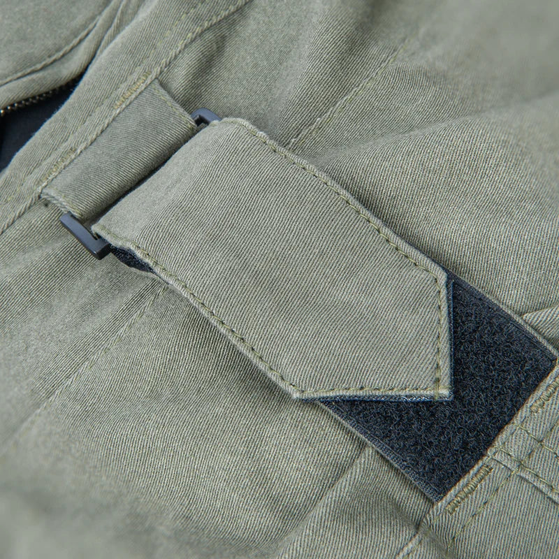 Close-up detail of an olive green canvas waist adjustment and a dark gray hook-and-loop fastener.