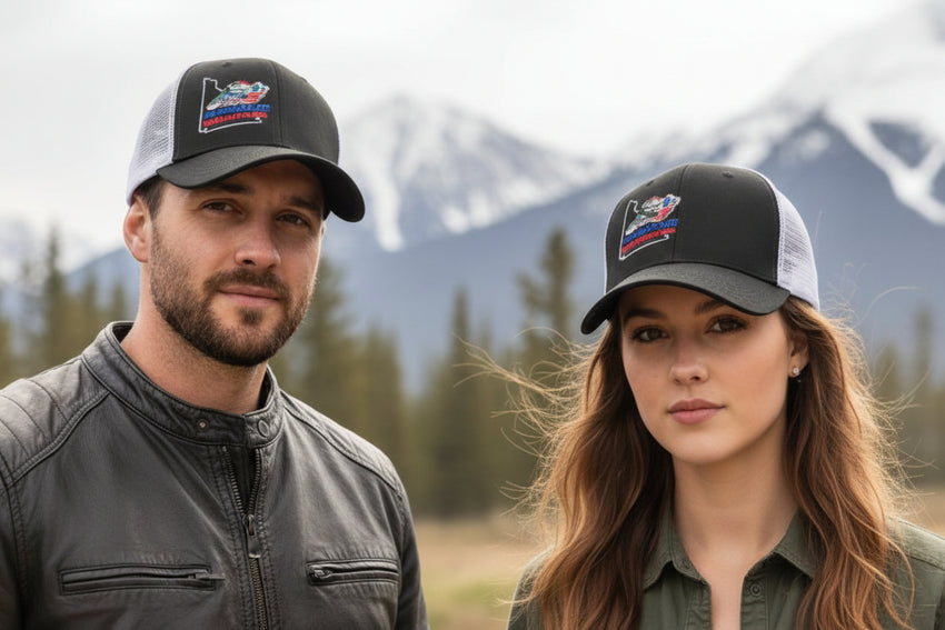 Two people wearing black and white caps with YMGA logos against a mountainous background