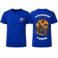 Front and back of a royal-blue YMGA Whitehorse Yukon T-shirt featuring a caribou in sunglasses riding a red cruiser motorcycle at sunset.