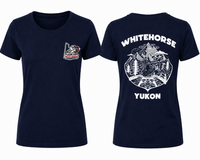 Women's navy blue T-shirt featuring a small Yukon Moto Gear & Apparel logo on the left chest. The back displays a bold white Whitehorse, Yukon graphic with mountains, trees, a lake, and off-road handlebars, celebrating adventure in the Yukon.
